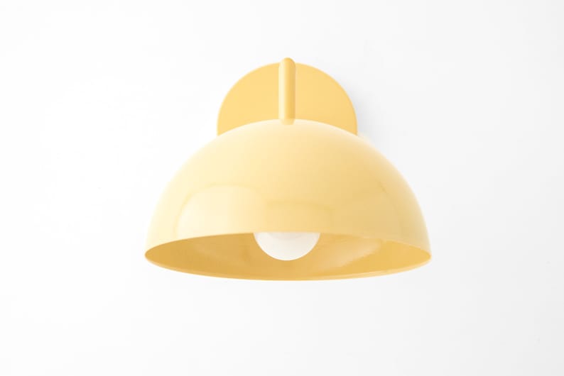 Puede incluir: Una l&aacute;mpara de pared de forma de c&uacute;pula amarilla con una sola bombilla.