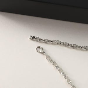 May include: A silver chain necklace with a lobster clasp and a small ball at the end. The chain is made of small, linked circles.