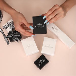 May include: Five small boxes with the word "BOEMO" printed on them. Two boxes are black and three are white.