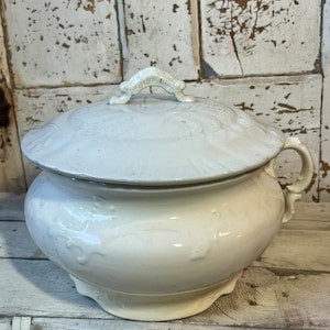 May include: White ceramic chamber pot with a lid and a handle. The pot has a floral design and is in a vintage style.