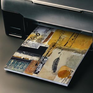 Op de afbeelding: Een zwarte inkjetprinter die een vel papier met een collageontwerp uitwerpt. De print toont een mix van mosterdgele, zwarte en cr&egrave;mekleurige texturen, inclusief een gedetailleerde zwarte veerillustratie, geometrische patronen en tekst.