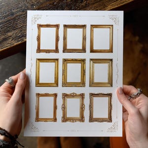 May include: A sheet of paper displaying nine decorative gold-coloured picture frame designs. The frames have various ornate styles and details. The paper is held by hands, highlighting the frames' potential use for art or photography.