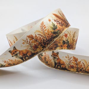 Könnte beinhalten: Ein cremefarbenes Stoffband mit einem sich wiederholenden Muster aus orangefarbenen Füchsen, die zwischen herbstlich gefärbtem Laub wie braunen, gelben und grünen Blättern, Farnen und Beeren sitzen, gedruckt in einem detaillierten, realistischen Stil.