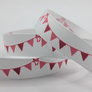 May include: White grosgrain ribbon featuring a repeating pattern of red pennant flags. The flags have a dotted texture and are connected by a red bow. The ribbon is coiled in a spiral.