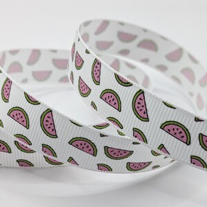 May include: White ribbon featuring a repeating pattern of pink and green watermelon slices. The ribbon has a ribbed texture, suitable for crafting, gift wrapping, or adding a decorative touch to various projects.