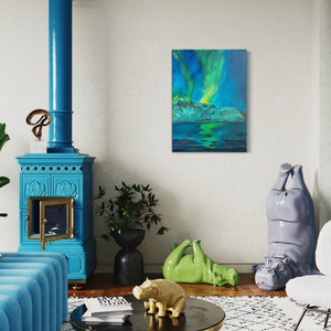 Può includere: Un dipinto che rappresenta l'aurora boreale sopra un corpo d'acqua blu scuro con montagne sullo sfondo. Il dipinto è incorniciato e appeso a una parete bianca in un soggiorno.
