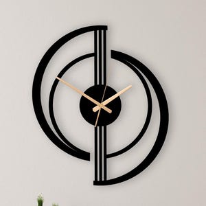 Puede incluir: Un reloj de pared con un marco geométrico negro compuesto por dos arcos semicirculares entrelazados y líneas verticales. El centro del reloj tiene un núcleo circular negro sólido con manecillas metálicas delgadas y claras.