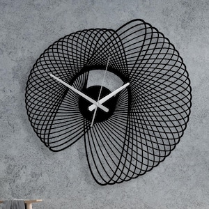 Puede incluir: Un gran reloj de pared negro y geométrico con un diseño abstracto único. El reloj presenta una esfera circular con manecillas blancas y un patrón lineal en espiral. Está montado en una pared de hormigón gris, añadiendo un toque moderno a la habitación.