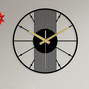 May include: A contemporary black and gold wall clock. The clock has a circular frame with gold hands and a black centre. It is mounted on a white wall, adding a stylish touch.