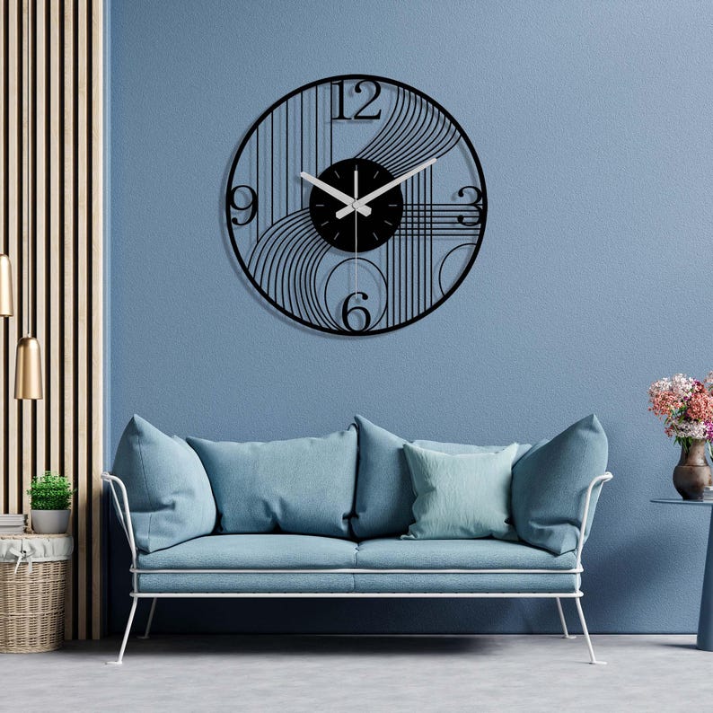 May include: A black and white geometric wall clock with a black background and white hands. The clock is hanging on a blue wall above a light blue sofa.