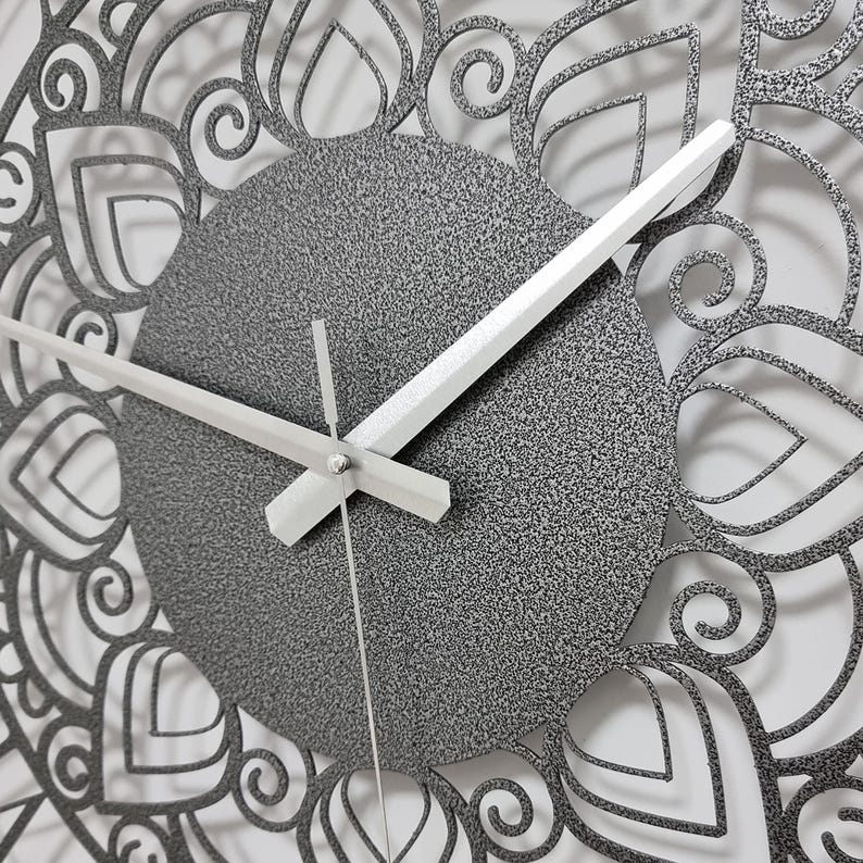 May include: A silver clock with a decorative mandala design around the edge. The clock face is gray with white hands.