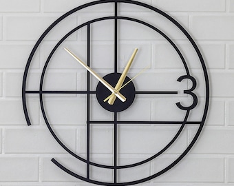 May include: A modern black wall clock with gold-colored hands and a black circular face. The clock features a unique design with a grid pattern and the number 3. The clock is mounted on a white brick wall.