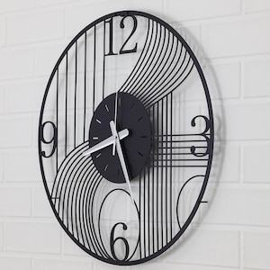 May include: Black and white metal wall clock with a geometric design. The clock face is black with silver hands and Roman numeral markings.