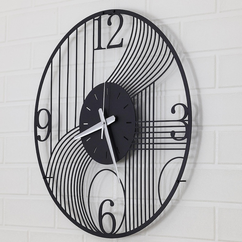 May include: Black and white metal wall clock with a geometric design. The clock face is black with silver hands and Roman numeral markings.