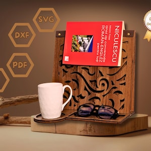 May include: A wooden book stand with a carved design holds a book with a red cover. A white mug sits on a small wooden coaster, and a pair of glasses rests on the stand. The stand has the text "NICULESCU" on the book.