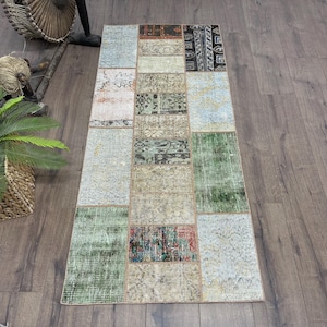 May include: A rectangular patchwork rug with a variety of colors and patterns. The rug is composed of rectangular and square patches in shades of green, blue, beige, and red. The rug is placed on a wooden floor.