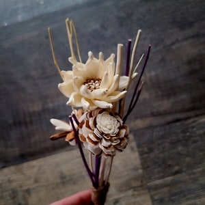 Peut inclure: Un bouquet de fleurs séchées avec des fleurs blanches et crème et des tiges violettes. Les fleurs sont disposées en bouquet lié à la main.