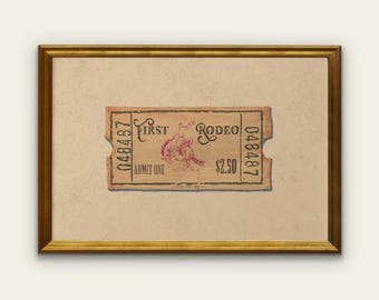 May include: A framed vintage rodeo ticket with a tan background and a gold frame. The ticket is tan with red text and a graphic of a rodeo rider. The ticket reads "First Rodeo" and "Admit One".