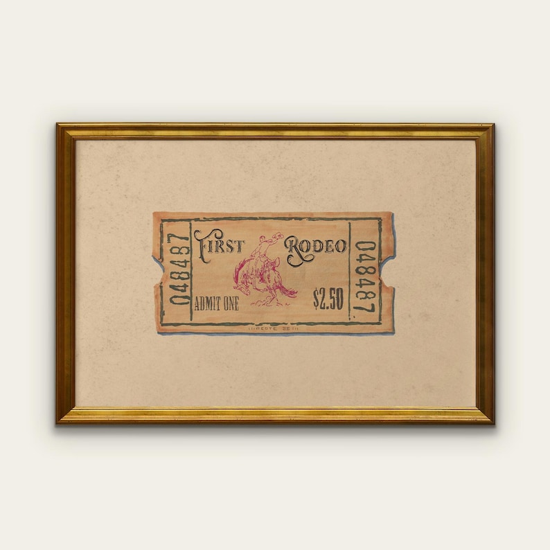 May include: A framed vintage rodeo ticket with a tan background and a gold frame. The ticket is tan with red text and a graphic of a rodeo rider. The ticket reads "First Rodeo" and "Admit One".