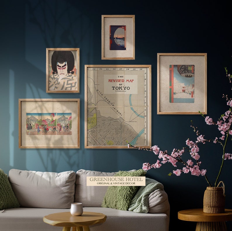 Puede incluir: Un interior de sala de estar con un sof&aacute; gris claro, una mesa de caf&eacute; de madera y un jarr&oacute;n de flores rosas. La pared es de color azul teal oscuro y presenta cinco impresiones enmarcadas, incluyendo un mapa vintage de Tokio, una impresi&oacute;n japonesa en madera y una escena de paisaje.