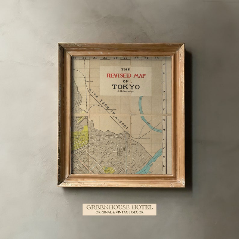 Puede incluir: Un mapa vintage enmarcado de Tokio, Jap&oacute;n, con el t&iacute;tulo "The Revised Map of Tokyo" en letras rojas. El mapa est&aacute; en un marco de madera claro y tiene un fondo marr&oacute;n claro. El mapa muestra las calles y v&iacute;as fluviales de la ciudad. El texto "GREENHOUSE HOTEL ORIGINAL & VINTAGE DECOR" est&aacute; impreso debajo del marco.