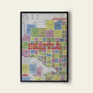 May include: A framed vintage map of Seattle, Washington. The map displays a colourful grid of city blocks, with the word "SEATTLE" in large red letters across the centre. The word "HUGHBANKS" is at the top.