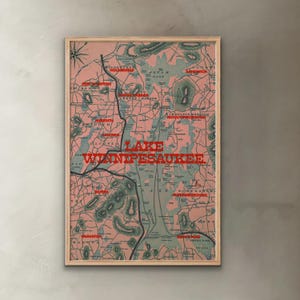 May include: A framed vintage map of Lake Winnipesaukee, New Hampshire, in a muted color palette of pink, green, and brown. The lake's name is prominently displayed in red. The map is enclosed in a wooden frame.