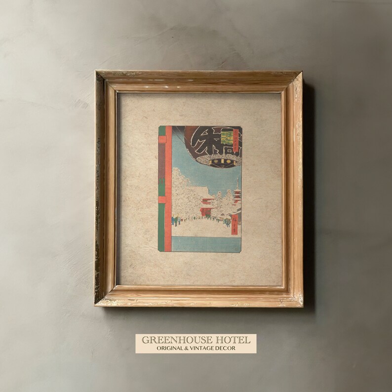 Puede incluir: Una impresi&oacute;n japonesa vintage enmarcada que representa una escena nevada con una puerta torii roja y una linterna. La impresi&oacute;n est&aacute; en un marco de madera claro y tiene un passe-partout de color crema.