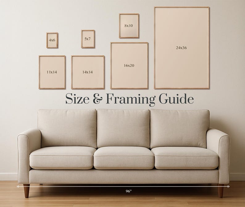 May include: A beige sofa with wooden legs is positioned below a wall displaying framed art prints of various sizes. The text "Size & Framing Guide" is displayed above the sofa. The sofa is 96 inches wide.