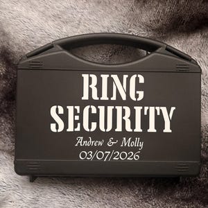 May include: A black case with a handle and the words "RING SECURITY" in large white letters. Below, the names "Andrew & Molly" and the date "03/07/2026" are printed in white.