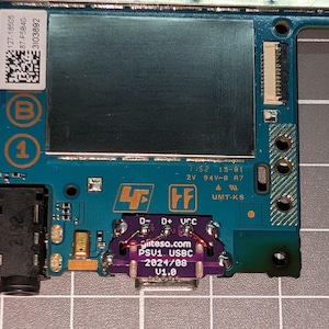 May include: A close-up of a circuit board with various electronic components. The board is primarily teal and green, with a purple USB-C port. Text on the board includes "tesa.com PSU1 USBC 2024/08 V1.0".