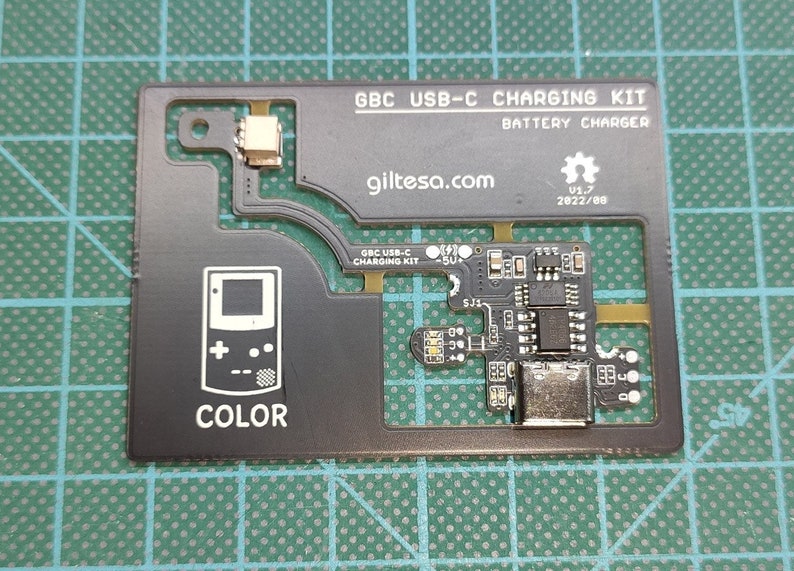 以下が含まれることがあります： 「GBC USB-C CHARGING KIT」と「giltesa.com」の文字が入った黒色のGBC USB-C充電キット。バッテリーチャージャーとゲームボーイカラーの図が含まれています。