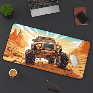 Può includere: Tappetino per scrivania rettangolare con un'illustrazione a cartoni animati di un monster truck in un paesaggio desertico. Il tappetino è principalmente marrone e beige, con un cielo blu e formazioni rocciose arancioni. Sono visibili anche un mouse bianco e una tazza di caffè.