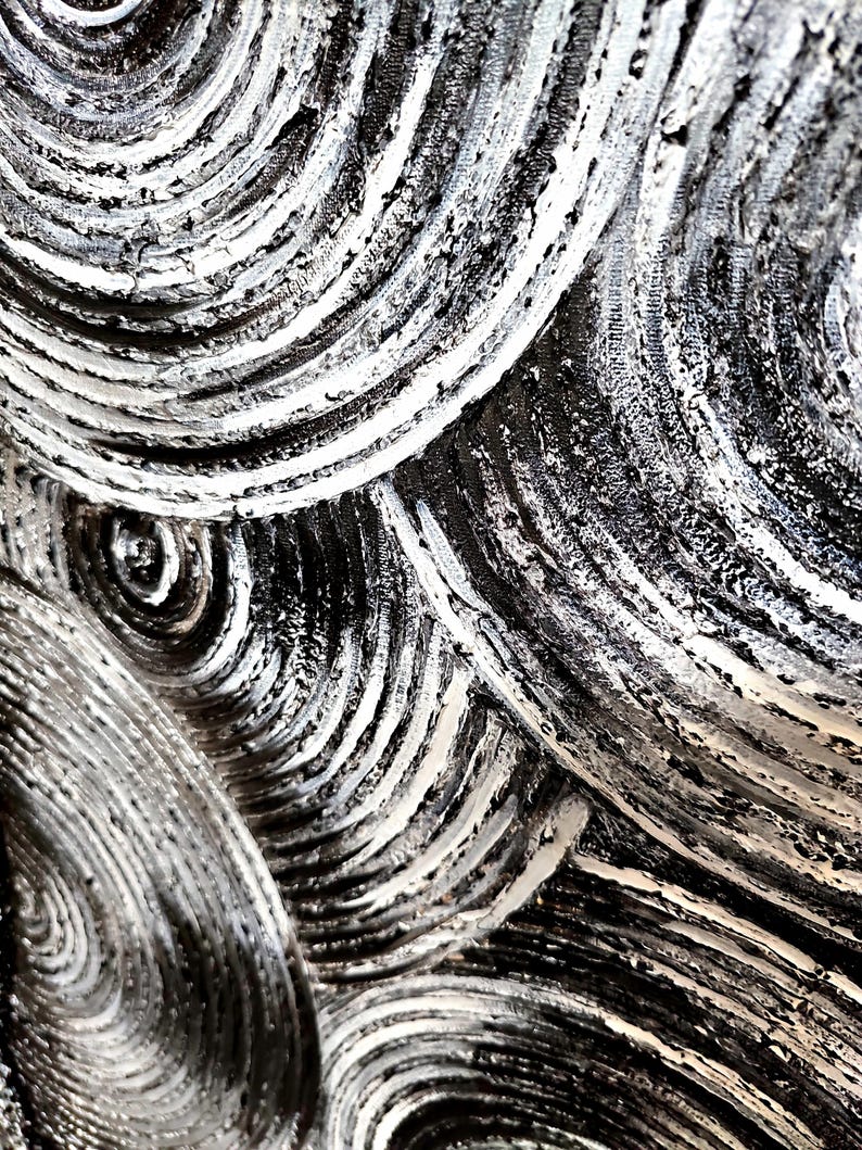May include: Abstract artwork featuring a close-up view of textured, swirling patterns. The design uses a palette of black, white, and gray, with thick brushstrokes creating a sense of depth and movement. The artwork's focus is on the interplay of light and shadow.
