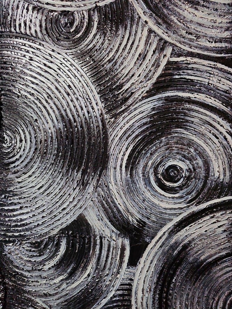 May include: Abstract artwork featuring overlapping concentric circles in shades of black and white. The textured surface creates a sense of depth and movement, with the white paint highlighting the spiral patterns.