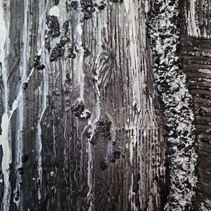 May include: Abstract art piece with a textured surface. The artwork features a combination of black, white, and gray tones. Dripping white paint and small black textured elements are visible, creating a dynamic visual effect. The piece has a rough, tactile quality.