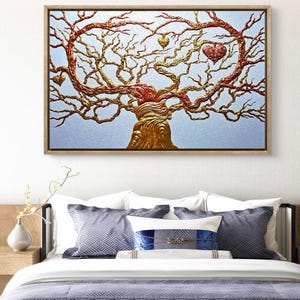 Può includere: Un'opera d'arte incorniciata raffigurante un albero stilizzato con rami dorati e rossi e accenti a forma di cuore. Il tronco dell'albero è dorato e lo sfondo è azzurro. L'opera d'arte è esposta sopra un letto con biancheria da letto blu e bianca.