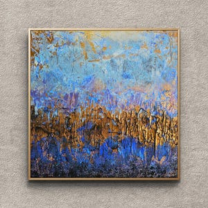 Può includere: Dipinto astratto strutturato in una cornice dorata. L'opera presenta una miscela di tonalità blu, oro e nero, con una superficie strutturata. Il dipinto evoca un paesaggio o una scena naturale.