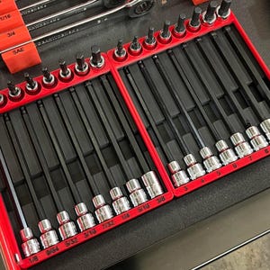 May include: A set of tools, including wrenches and hex keys, neatly organized in a red tray. The tools are arranged in rows, with sizes labeled in inches. The image showcases a variety of tools for mechanical work.