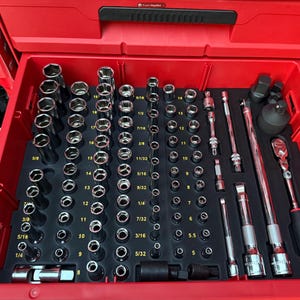 May include: A red toolbox drawer filled with a variety of chrome sockets, extensions, and ratchets. The tools are neatly organized in a black foam insert, with sizes labeled in inches. A Snap-on ratchet is visible.