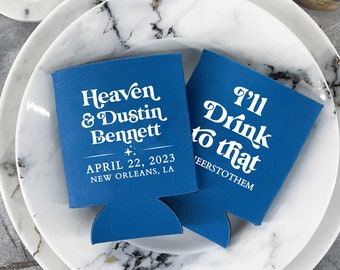 May include: Two blue can coolers with white text. One cooler says "Heaven & Dustin Bennett" with the date "April 22, 2023" and "New Orleans, LA". The other cooler says "I'll Drink to that".