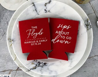 Peut inclure: Deux manchons de canettes rouges avec du texte blanc. L'un dit "The Floyds" avec des noms et une date. L'autre dit "sips about to go down". Les manchons sont sur une assiette en marbre avec des couverts et une boisson.