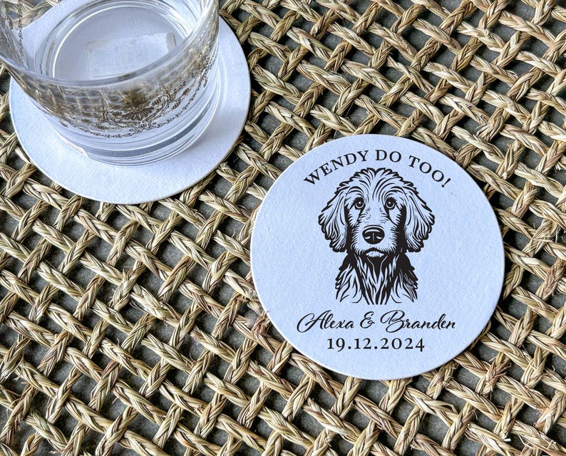 Op de afbeelding: Ronde witte onderzetter met zwarte tekst en een zwart-witte illustratie van een hond. De tekst luidt "Wendy Do Too! Alexa & Branden 19.12.2024".