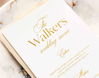 Könnte beinhalten: Eine weiße Hochzeitsmenükarte mit goldener Folienprägung, die The Walkers wedding menu, Entree und Mains zeigt. Der Text listet Speisen wie Meeresfrüchtesalat, Garnelen, Calamari, Scungilli, Muscheln und Prosciutto di Parma auf.