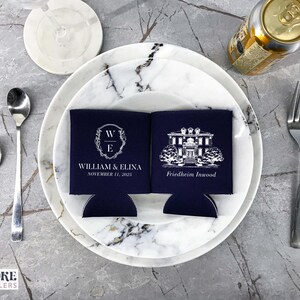 May include: Two navy blue can coolers with white text and designs. One cooler features a monogram with the initials "W" and "E" and the text "William & Elina, November 11, 2023". The other cooler features a black and white illustration of a house with the text "Friedheim Innwood".