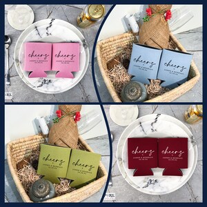 Pu&ograve; includere: Quattro set di portabevande personalizzati in rosa, blu, verde e bordeaux. Ogni portabevande ha la parola "cheers" in corsivo, insieme a un nome e una data. I portabevande sono disposti su piatti e in cesti.