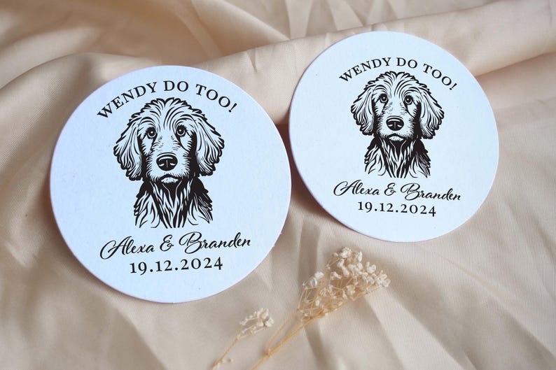 Op de afbeelding: Twee ronde witte onderzetters met zwarte hondenillustraties en de tekst "WENDY DO TOO!" Alexa & Branden 19.12.2024.