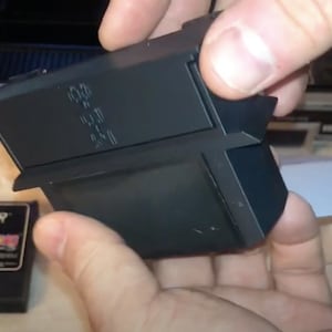 May include: A black plastic cartridge for a vintage video game console. The cartridge has a label with the text "10.0 9.0 8.0 7.0 6.0 5.0 4.0 3.0 2.0 1.0 0.0"