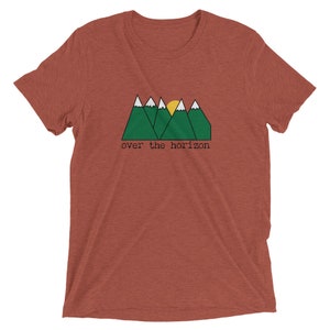 May include: A red t-shirt with a green mountain range and a yellow sun graphic. The text "over the horizon" is printed below the graphic.