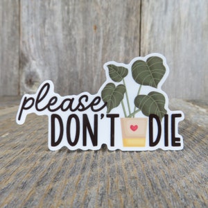 May include: White sticker with the text "please don't die" in black lettering. A cartoon illustration of a potted plant with green leaves is in the center of the sticker.